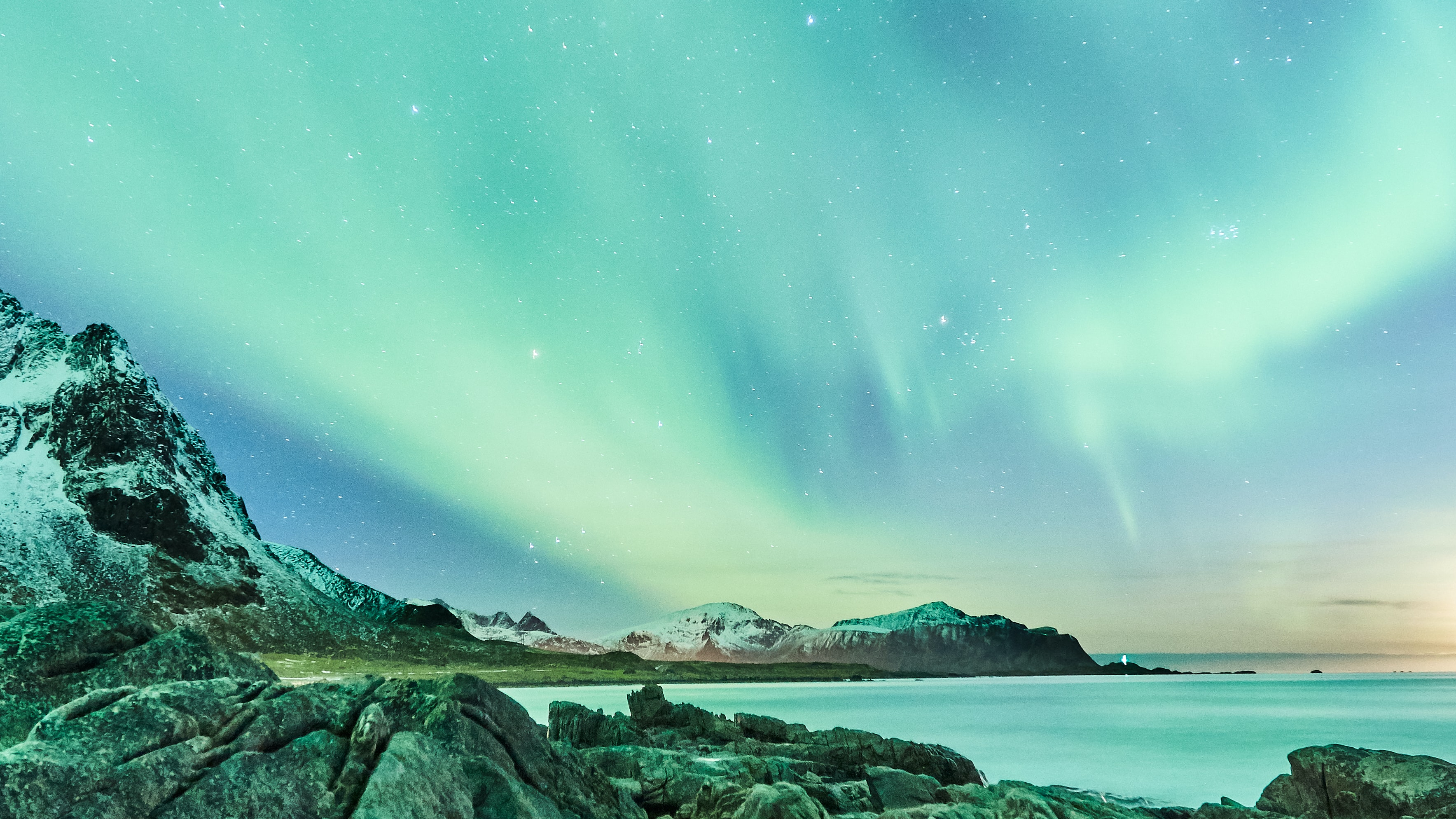 Aurora borealis above a rocky coastline.