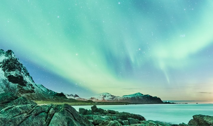 Aurora borealis above a rocky coastline.