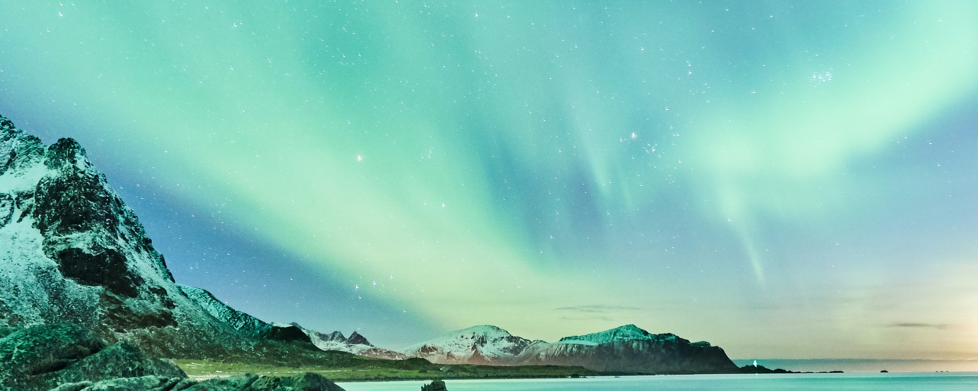 Aurora borealis above a rocky coastline.